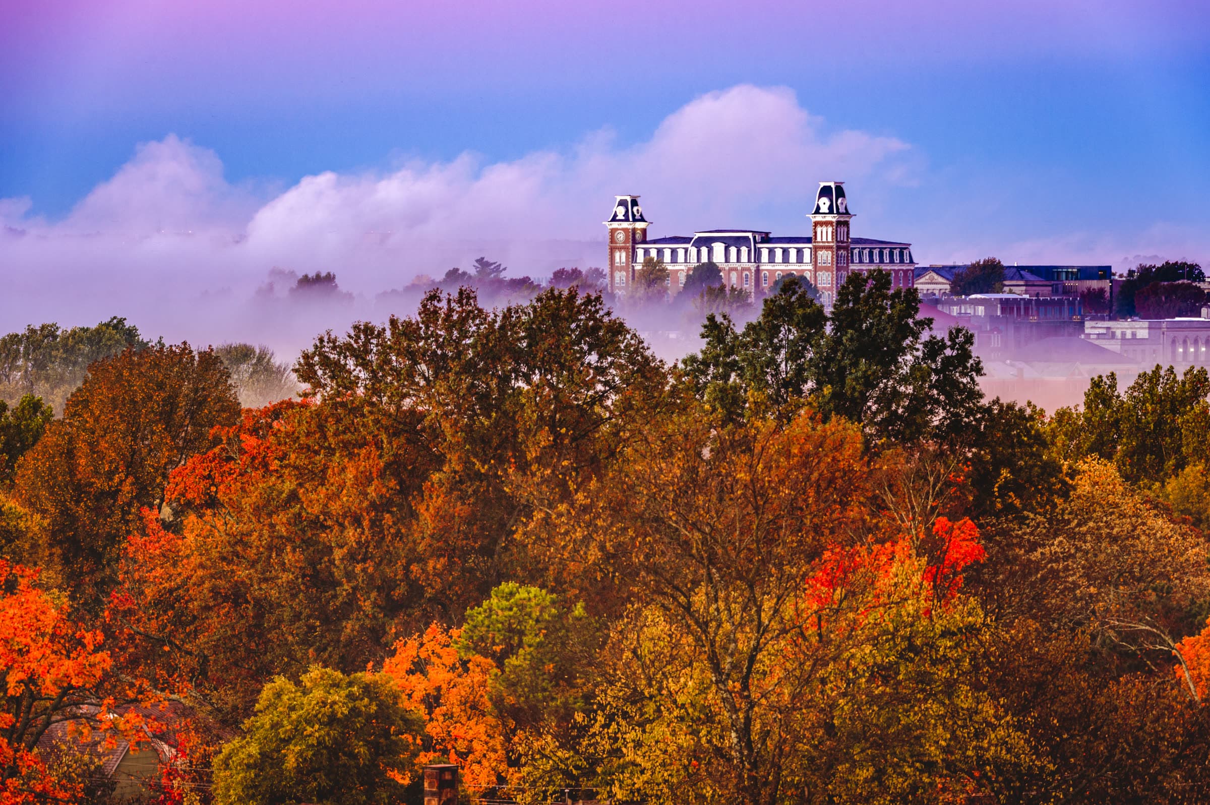 Old Main at the University of Arkansas in Fayetteville rising above morning fog and autumn trees